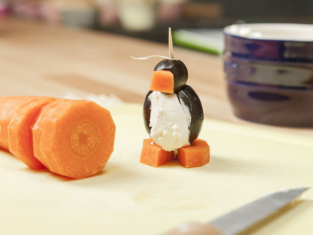 Ein Pinguin-Spieß steht auf einem Holzbrett